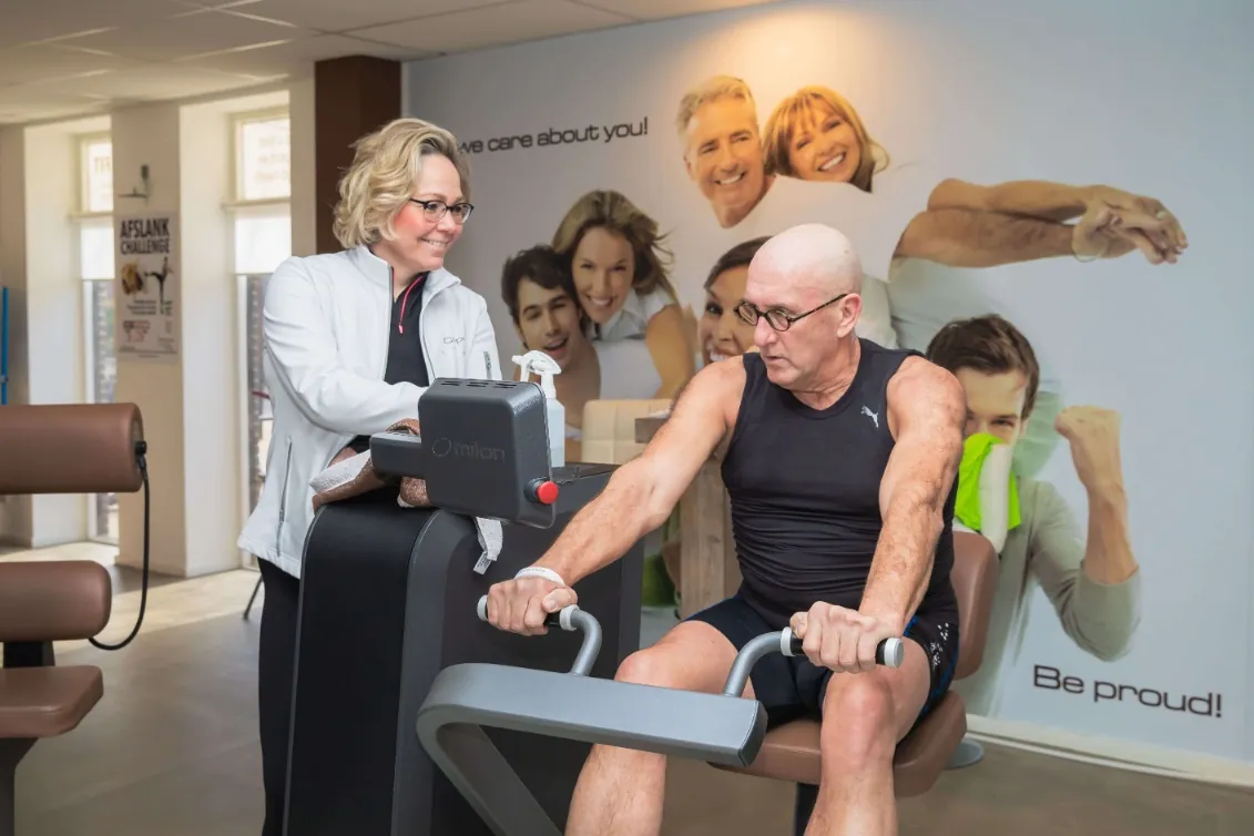 Coach begeleidt een man tijdens zijn training op een Milon-toestel